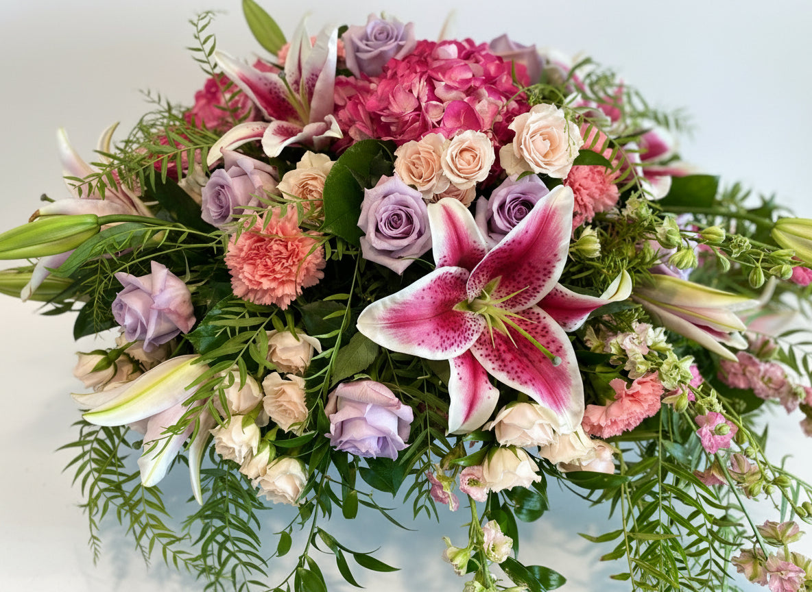 casket cover of flowers in pink, white, peach, lavender