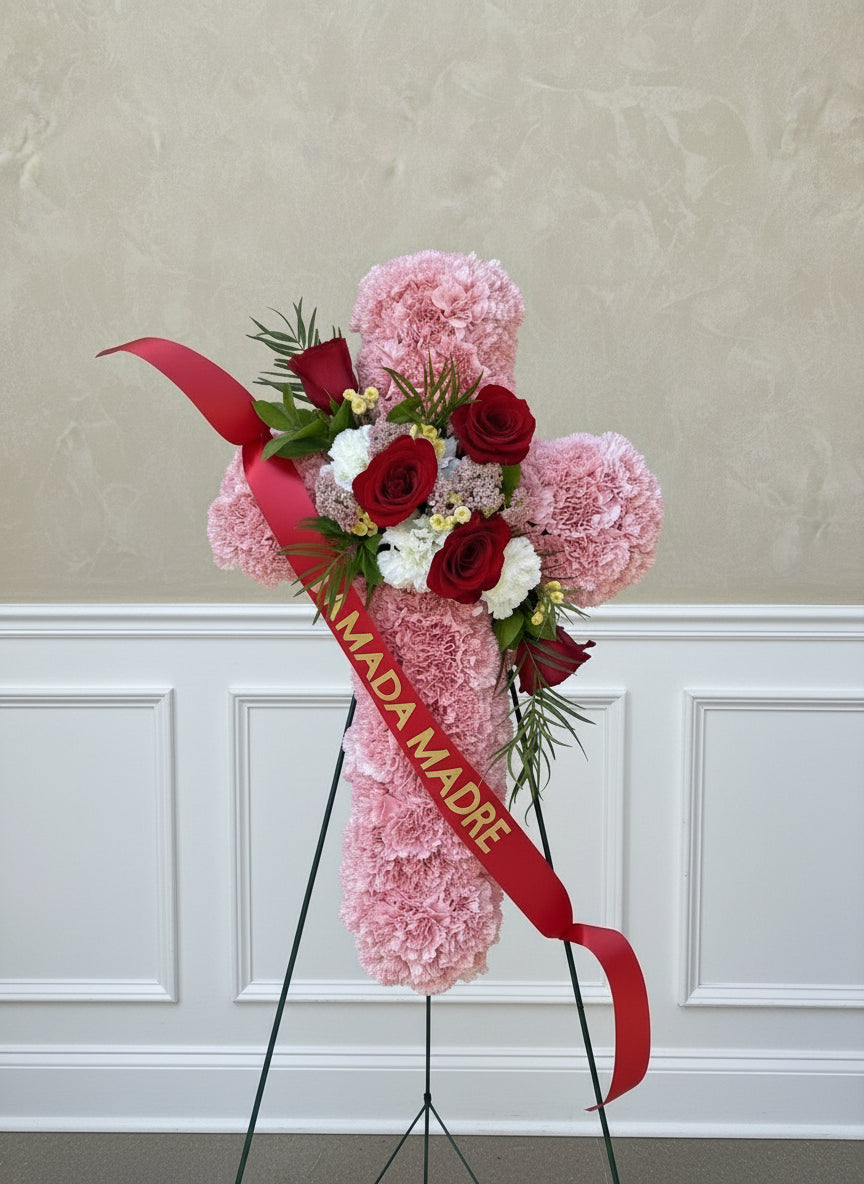 Floral arrangement with pink and red flowers on a stone surface, featuring a red ribbon with 'MADRE' text.