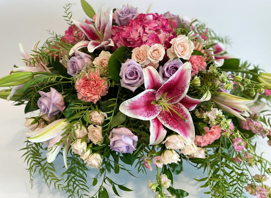 casket cover of flowers in pink, white, peach, lavender