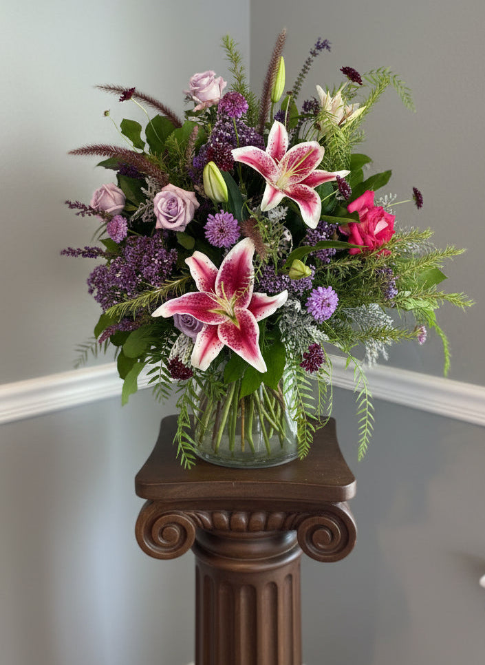 bouquet of flowers by Sarah Larkin Design on a pedestal in front of a gray wall